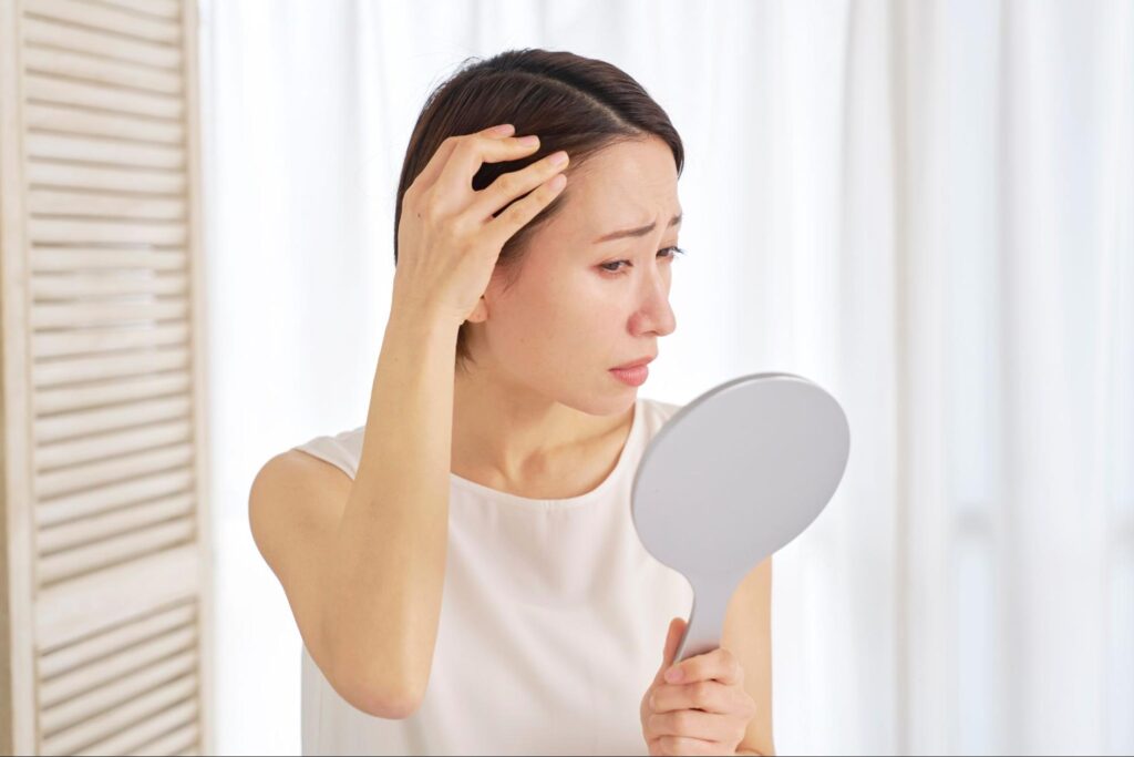 生え際を鏡で見る女性