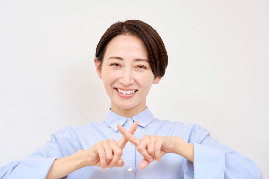 指でバツを作る女性