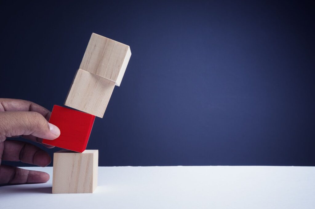 赤い積み木を抜こうとする手