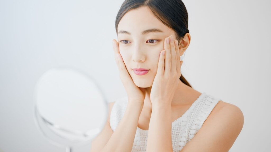 鏡を見ながら両頬を押さえる女性