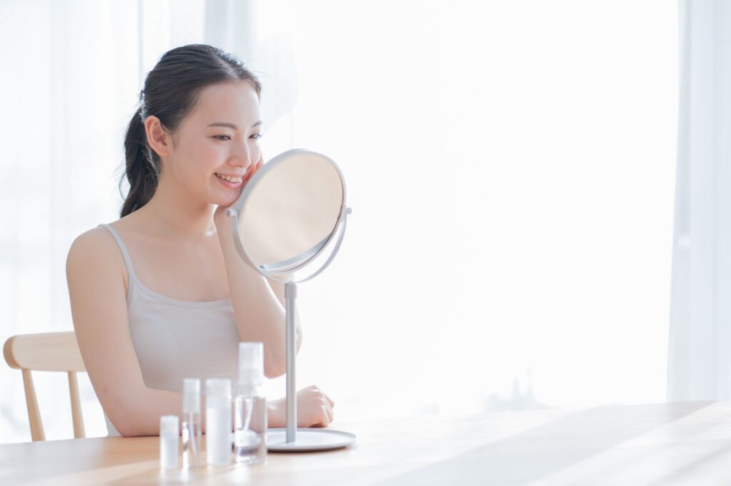 鏡で自分の肌を見て微笑む女性