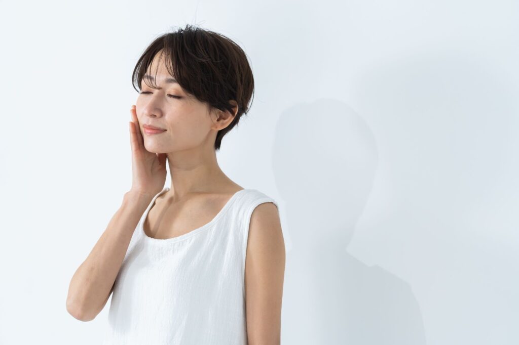 右手を頬に当てながら目をつぶる女性