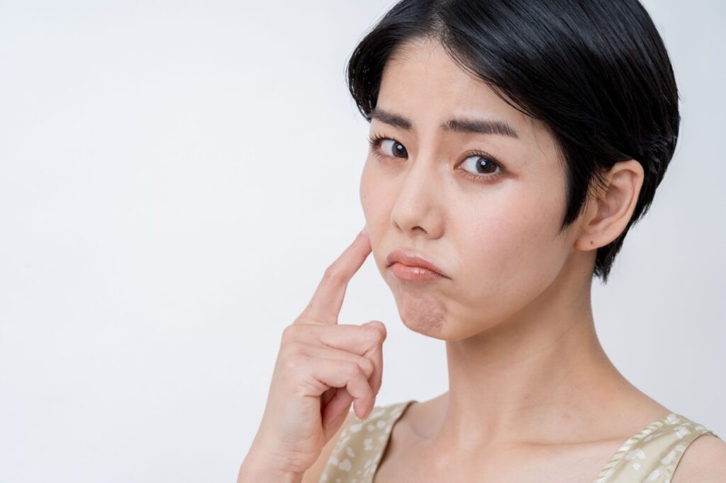 不満気に頬を指差す女性
