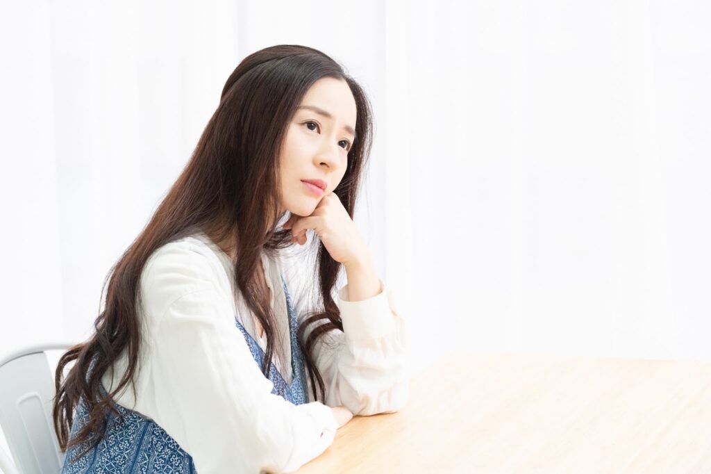 テーブルに肘を置いて考える女性