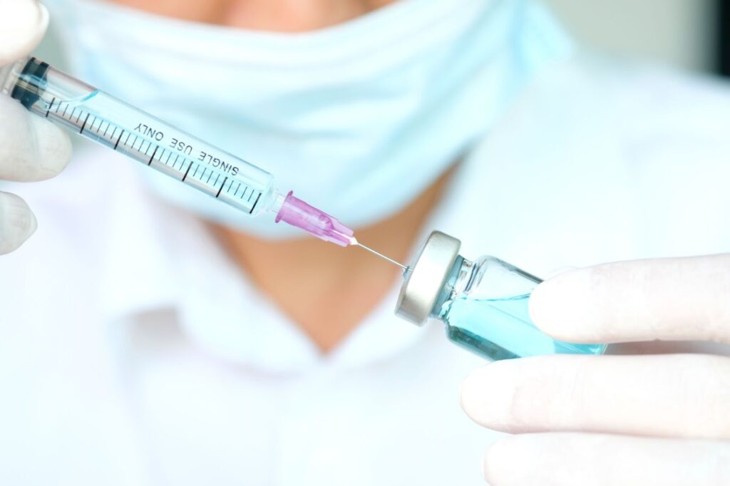 アンプルから注射器で薬剤を吸い上げる医療スタッフ