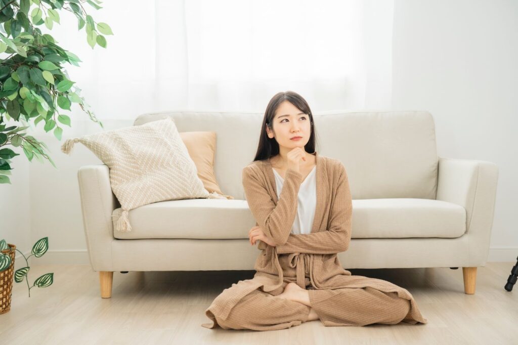 床に座って考え事をする女性