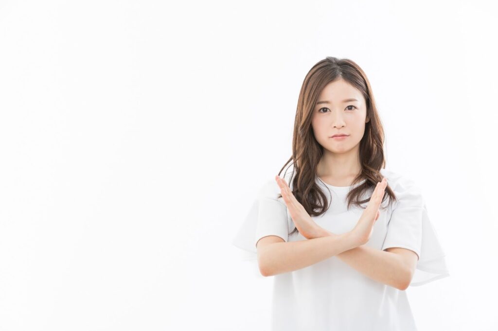 胸元でバツを作る女性