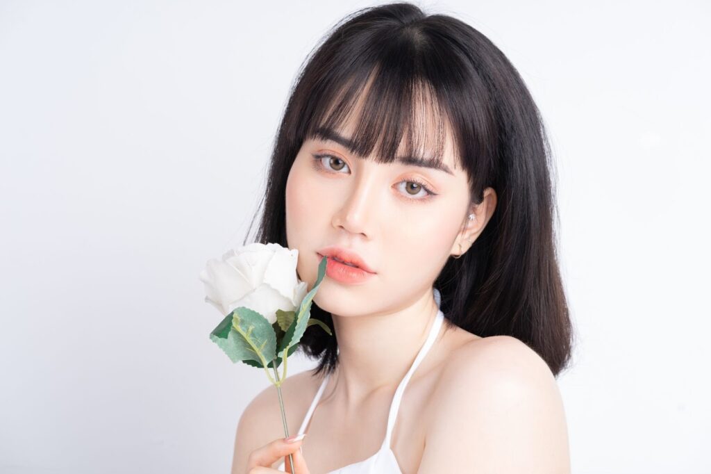 白いバラを手に持った女性