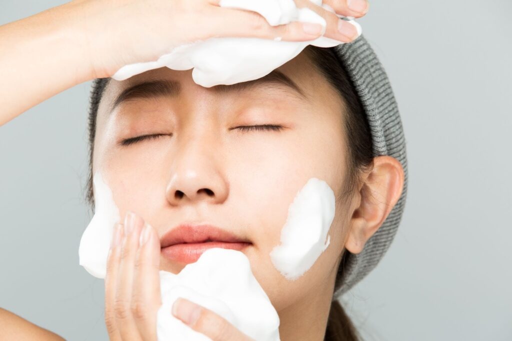泡立てた洗顔料で顔を洗う女性