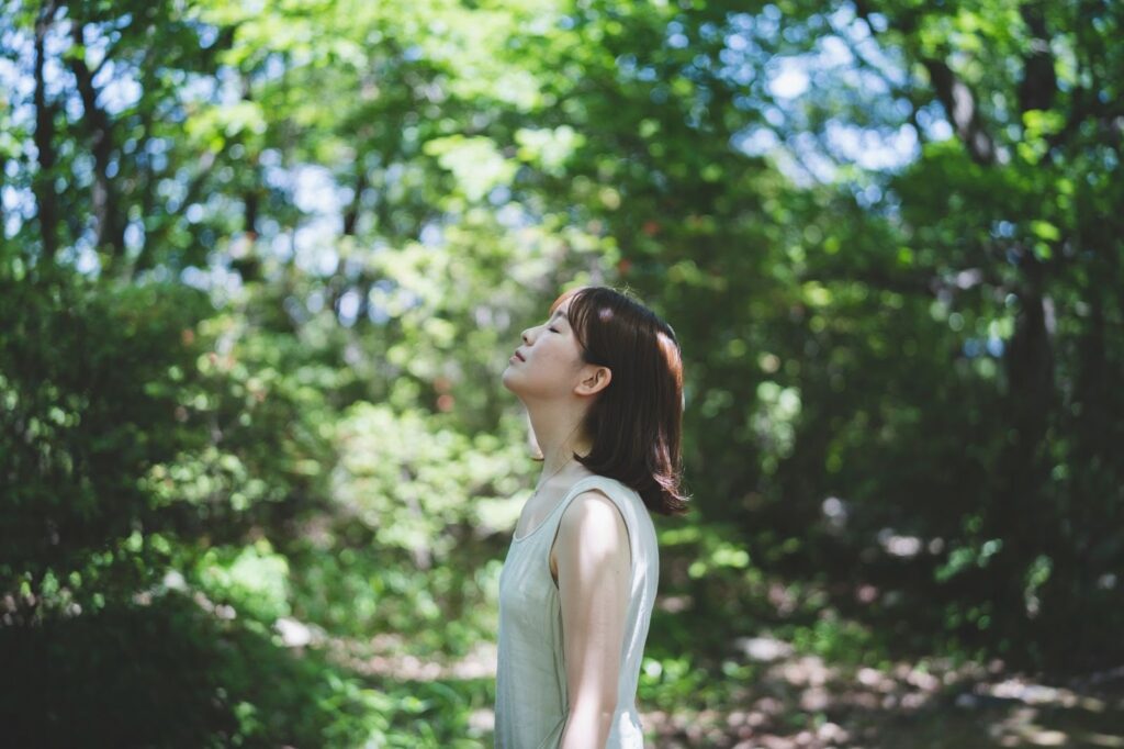 森の中で静けさを感じる女性