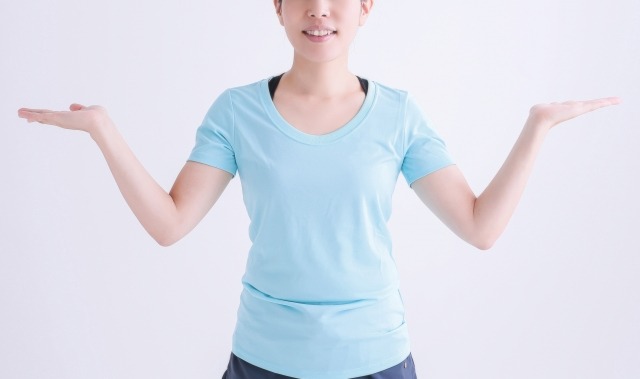両肘を曲げた腕を左右に広げる女性