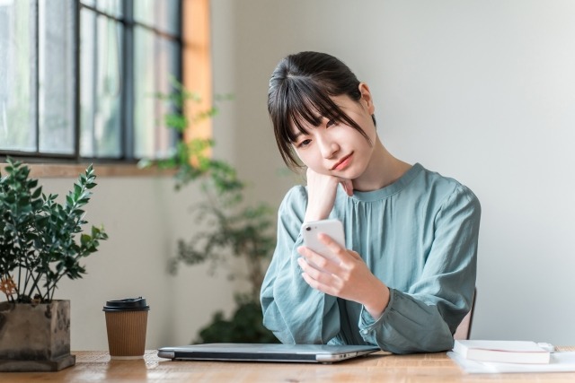 スマホを眺めながら考える女性