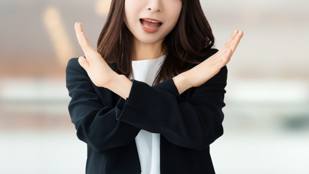 手でバツを作る女性