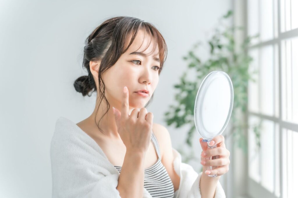 鏡で肌の調子を見る女性
