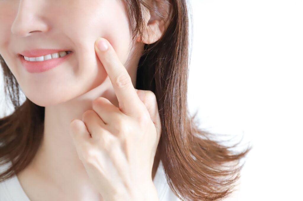 頬を指で押しながら微笑む女性