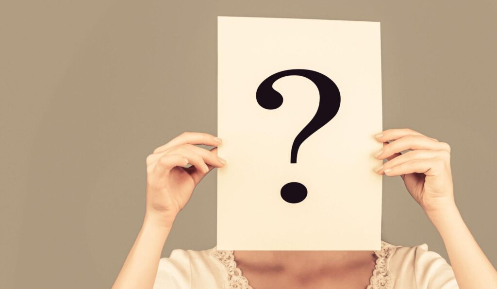 はてなマークの紙を顔の前にかざす女性