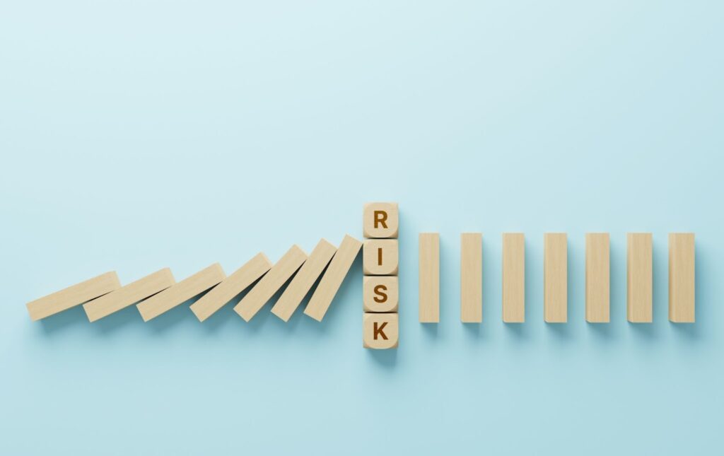 RISKと書かれたブロックが途中でドミノ倒しを止めている画像