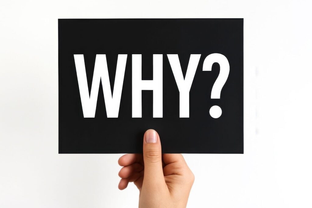 WHY?と書かれた紙とそれを持つ手