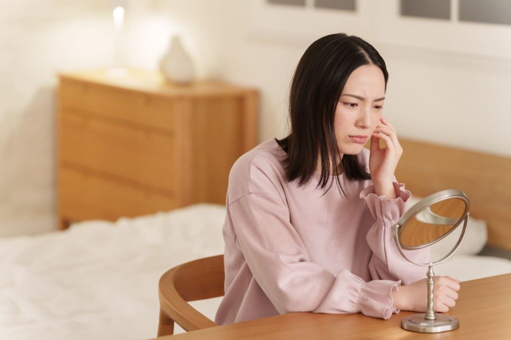 ニキビ跡を気にして鏡を見ている女性