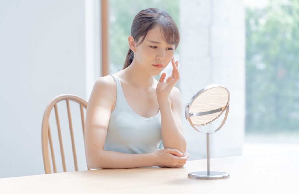 ニキビ跡を気にして鏡を見ている女性