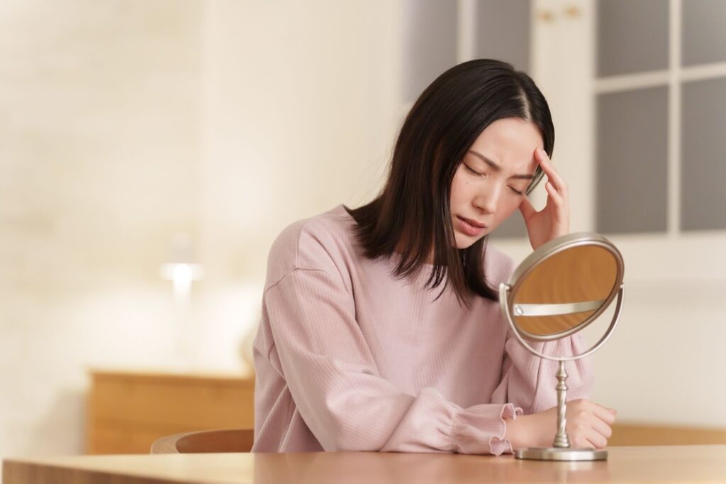 ニキビ跡を気にして鏡を見ている女性